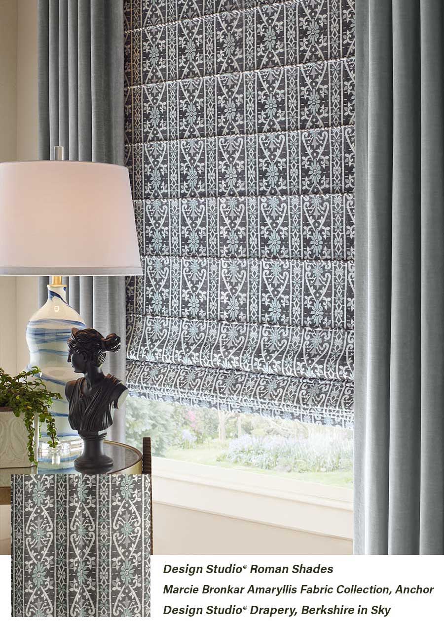 Patterned roman shades layered with draperies