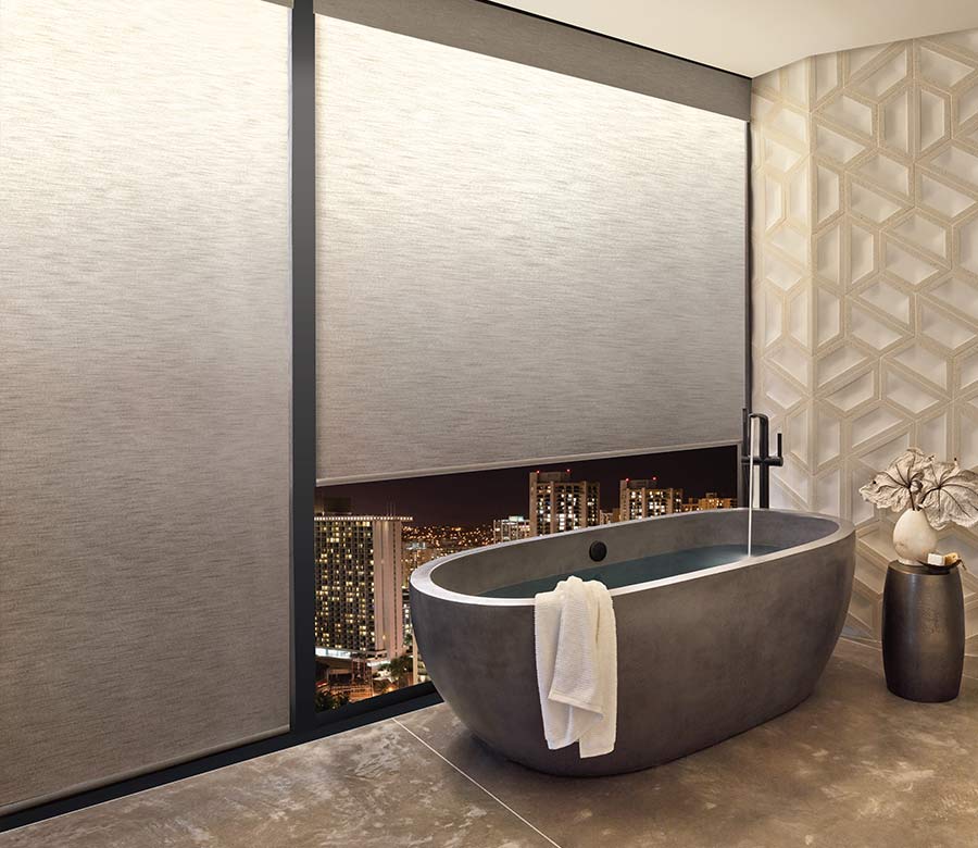 a modern bathroom with a tub next to large windows covered by illuminated privacy shades