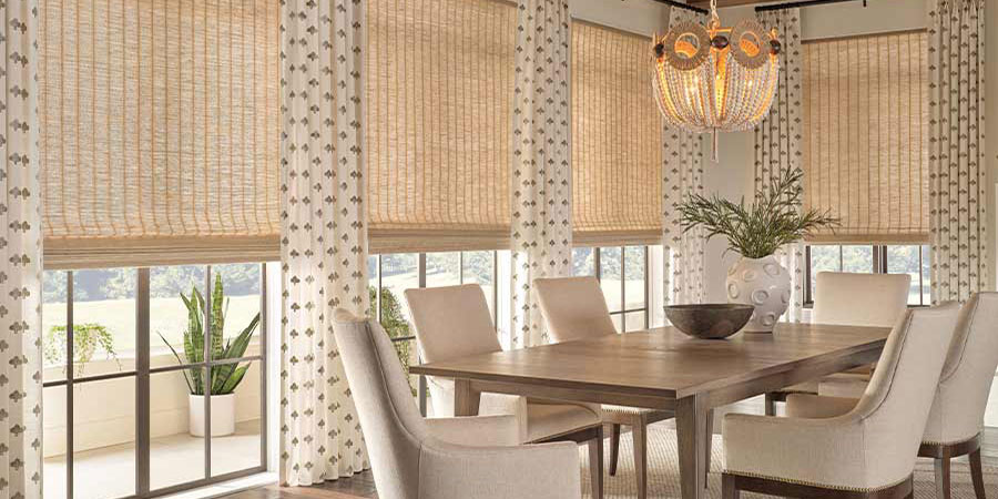 Patterned custom drapery layered with Provenance® Woven Wood Shades in a contemporary dining room
