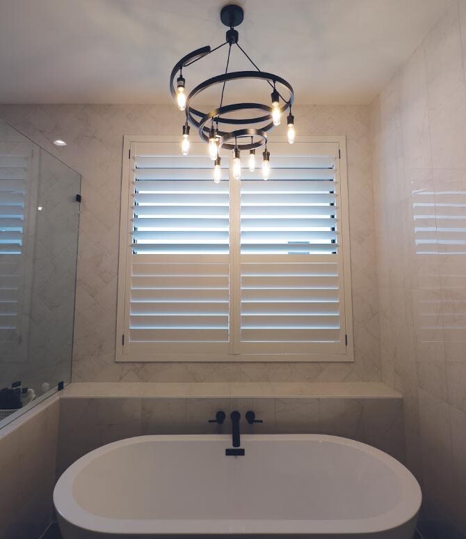 bathroom with white shutters and chandelier