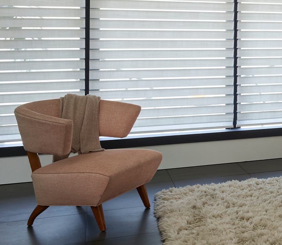 Hunter Douglas Silhouette sheer window shades behind an accent chair, gently filtering daylight through layered fabric vanes