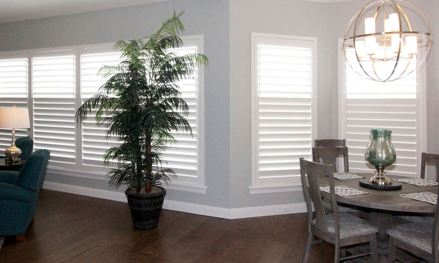 White plantation shutters on a wall of windows in an open floor plan